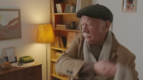 Senior Man Adjusts Scarf and Hat Indoors