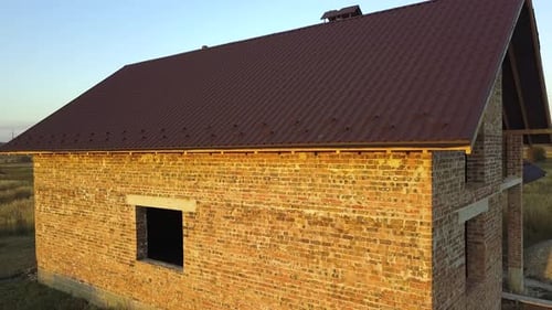 Aerial view of unfinished house with wooden roof structure covered with metal tile sheets under