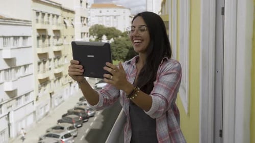 Smiling Woman Using Tablet Device on Balcony