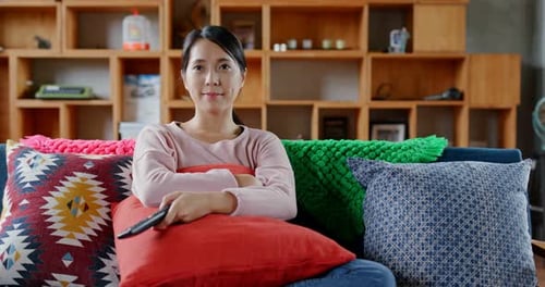 Woman Relaxing on Couch at Home with Remote