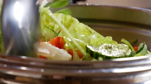 Mixing tender and moist vibrant salads in close up static view