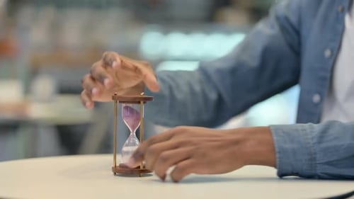 African Man Turning Over Hourglass Close Up