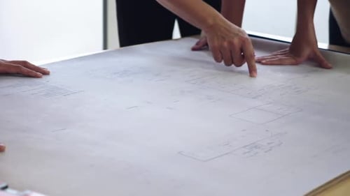 Team Collaborates on Architectural Blueprint in Office