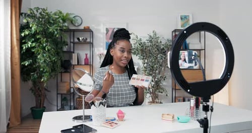 Joven influencer de belleza graba Vídeo para su canal de redes sociales usando el teléfono y la luz del anillo