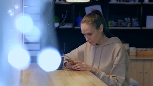 A young woman using smartphone in a evening cafe, drink coffee.