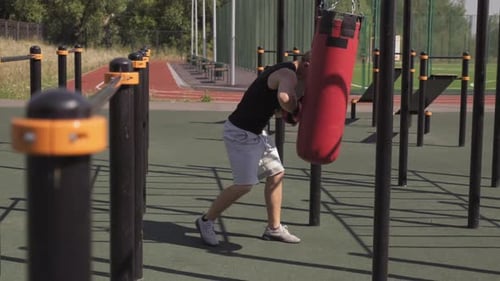 Young Adult Training Outdoors with Punching Bag