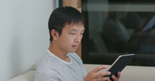Man Using Tablet Device While Relaxing Indoors