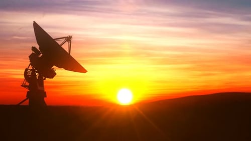Giant Satellite Dish Rotating in Silhouette Against a Sunset Sky