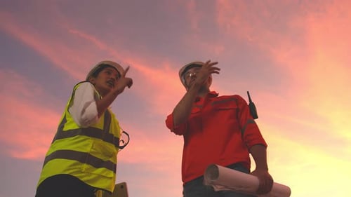 Smiling Engineers Shake Hands on Rooftop at Sunrise