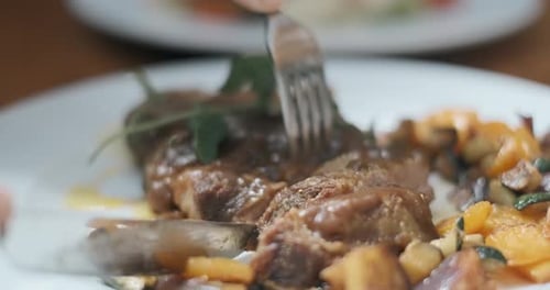Hände eines Mannes werden mit einem Messer geschnitten ein Fleischsteak Nahaufnahme. Jemand isst fettreiches Essen in der