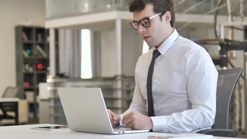 Young Adult Working on Laptop in Bright Office