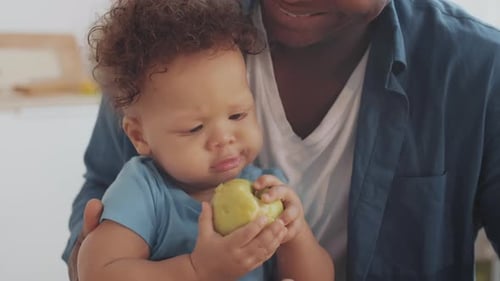 Adorable Infant Tastes Green Apple While Being Held
