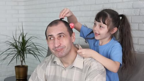 Girl Playfully Putting Hair Clips in Adult's Hair