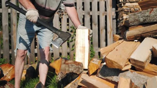 Starker männlicher Arbeiter, der Holz hackt und mit Axt auf Holzscheit schlägt