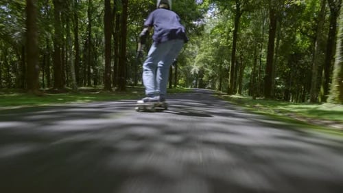Skateboarder Rolls Down Scenic Road on Summer Day