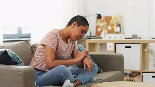 Woman Uses Smartwatch Sitting on Sofa Indoors