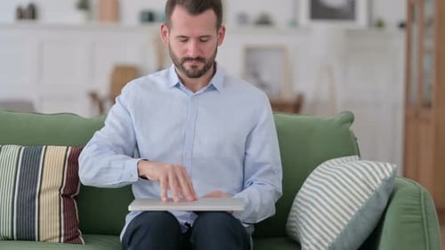Man Sitting on Couch Opens Laptop