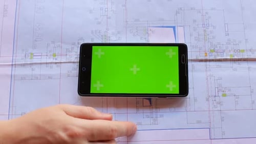 Construction engineer using a smartphone with a green screen looking for information on the internet