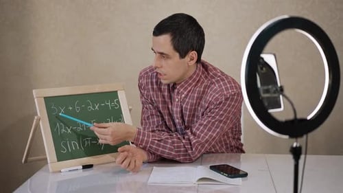 Man Teaching Math Lesson with Chalkboard and Phone