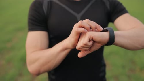 Adult Using Smartwatch Outdoors in Green Setting