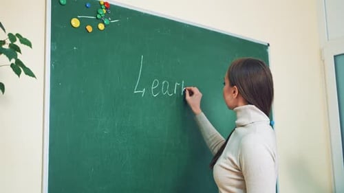 Enthusiastic Woman Writes 'Learn English' on Chalkboard