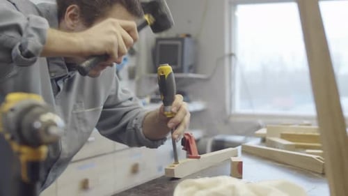 Man Working Wood with Chisel and Hammer