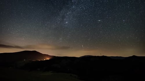 Stars with Milky Way Galaxy Moving in Starry Night Sky over Mountains in Rural Nature