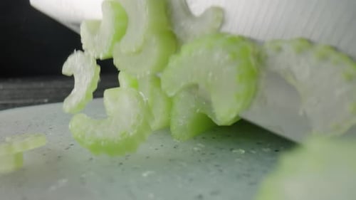Male Hands Cutting Celery Stalks with a Knife Into Small Slices