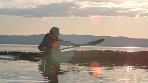 Kayaker Paddling on Calm Lake at Sunrise