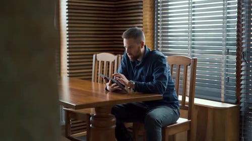 Man Using Tablet Device at Wooden Table