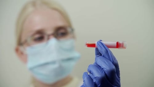 Technician Holding Vial of Blood Sample in Laboratory
