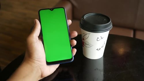 Junger Mann benutzt Smartphone mit Greenscreen in einem Café