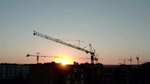 Aerial Drone View of Silhouette Construction Cranes in Sunset Light. Construction Site Building