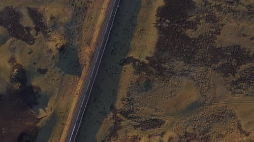 Aerial Shot of Empty Road in the Middle of Grassy Field Horizon in Iceland