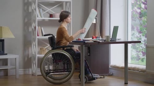 Qualifizierte professionelle behinderte Architektin analysiert Blaupause im Home Office drinnen