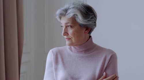 Senior Woman Contemplating, Looking Out Window Indoors
