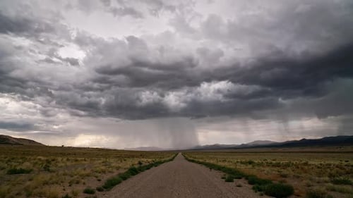 Timelapse of rainstorm looking down dirt road of into the desert landscape