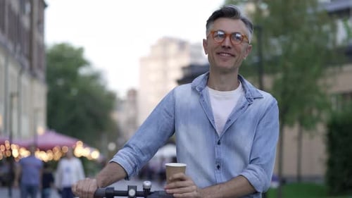 Homme marchant avec un scooter électrique