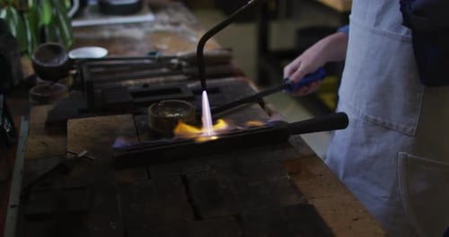 Mittelteil einer kaukasischen Juwelierin in Werkstatt mit Schürze, mit Gasbrenner