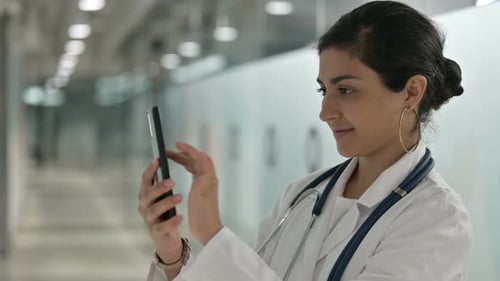 Relaxed Indian Female Doctor Using Smartphone in Cafe