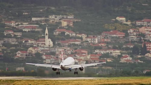The Plane Lands on the Runway at the Airport in the Cityscape