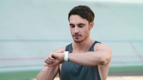 Man Checks Smart Watch at Outdoor Track