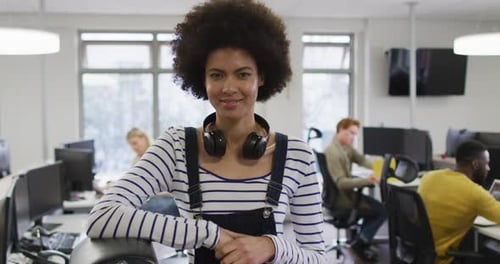 Portrait of smiling african american creative businesswoman sitting by desk in modern office