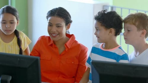 Teacher assisting schoolgirls in learning computer