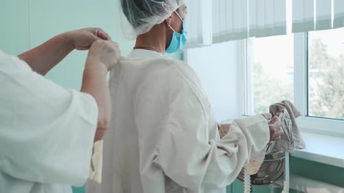 Surgical Nurses Preparing for Surgery Helping Each Other to Tie Protective Suit