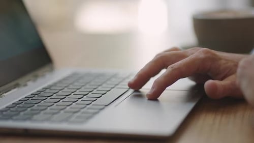 Close Up Hand of Man Scrolling a Website Using Laptop Track Pad