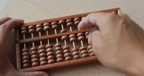 Hands Using Wooden Abacus to Calculate