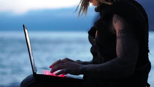 Person Using Laptop Computer near Ocean Water