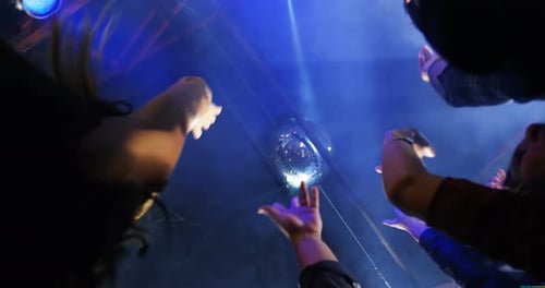 Enthusiastic Crowd Reaching for a Disco Ball at Night