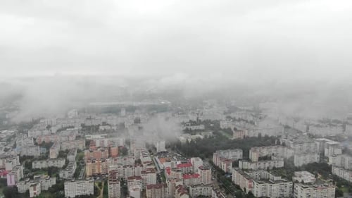 Aerial View Through Clouds Revealing Cityscape on a Foggy Day Pan Down